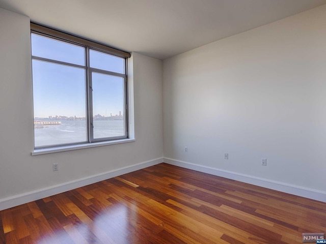 spare room featuring a water view and wood-type flooring