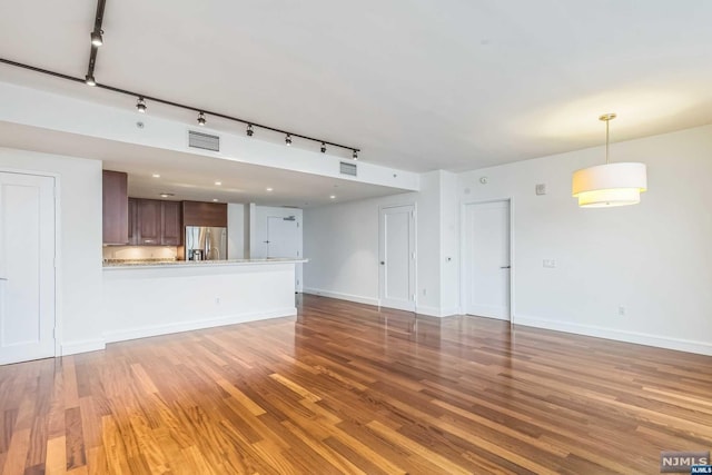 unfurnished living room featuring hardwood / wood-style floors and rail lighting