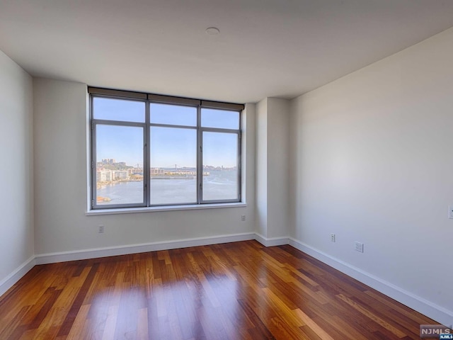 empty room featuring hardwood / wood-style floors and a water view