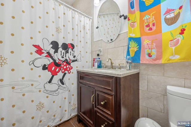 bathroom with vanity, tile walls, and toilet