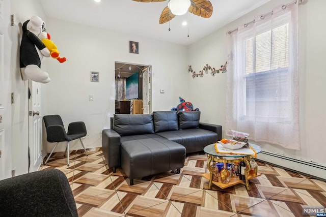 living room featuring ceiling fan, light parquet flooring, and a baseboard heating unit