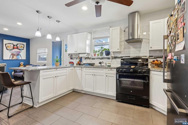 kitchen with stainless steel fridge, light stone counters, white cabinets, black gas range, and range hood