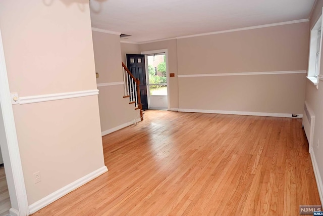 empty room with light wood-type flooring and ornamental molding