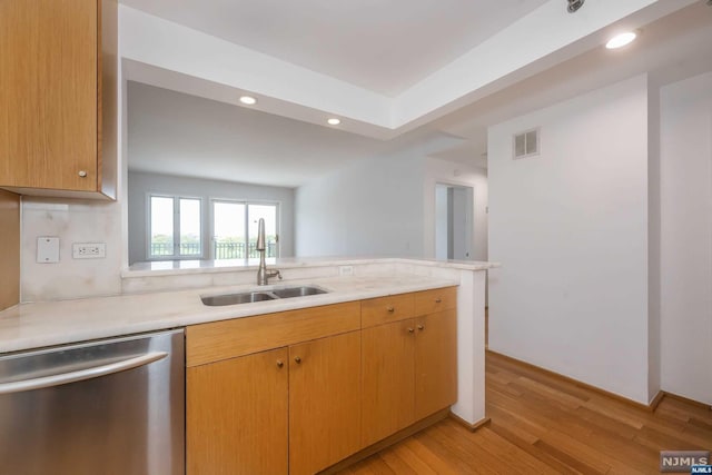 kitchen featuring dishwasher, light wood-type flooring, kitchen peninsula, and sink