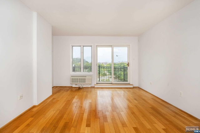 spare room featuring light wood-type flooring and a wall mounted AC