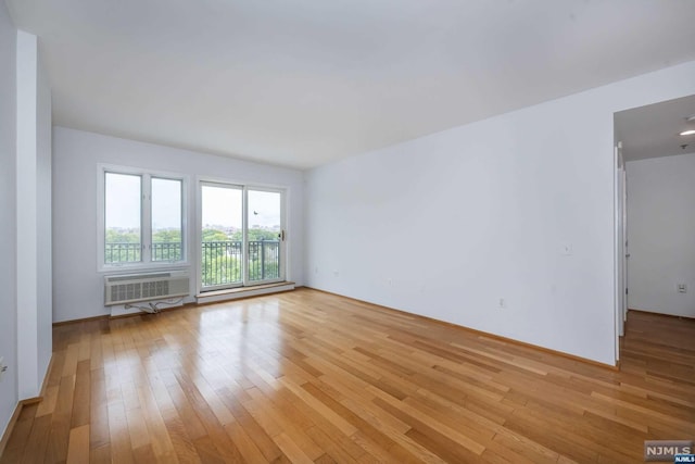 empty room featuring a wall mounted AC and light wood-type flooring