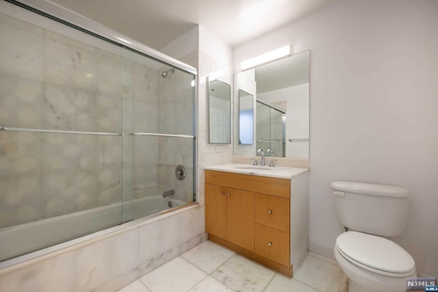 full bathroom with tile patterned flooring, vanity, combined bath / shower with glass door, and toilet