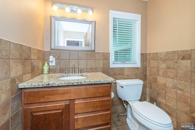 bathroom featuring vanity, toilet, and tile walls