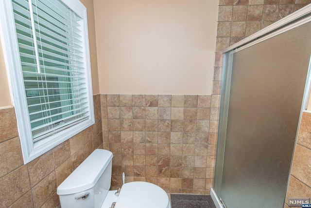 bathroom with a shower with door, tile walls, and toilet