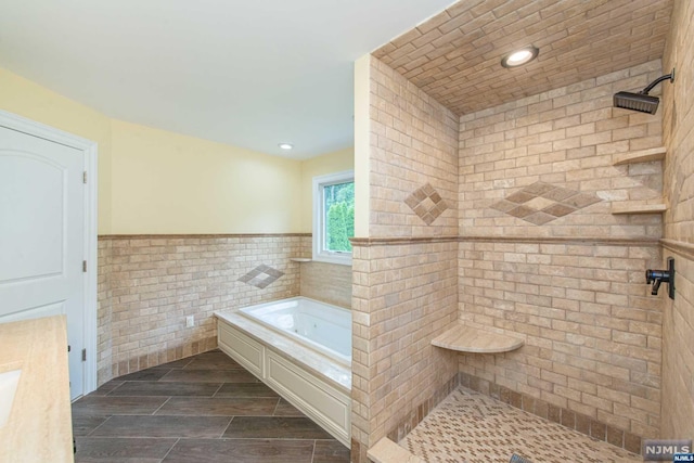 bathroom featuring shower with separate bathtub and tile walls