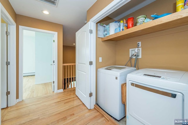 laundry area with light hardwood / wood-style floors, independent washer and dryer, and baseboard heating