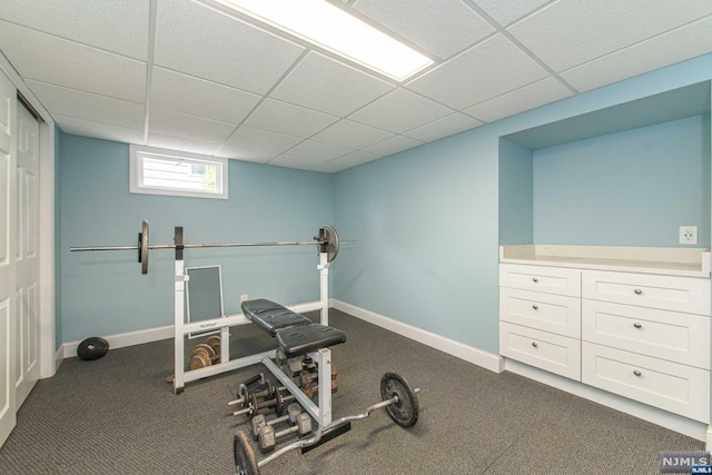 exercise area with a paneled ceiling and dark colored carpet