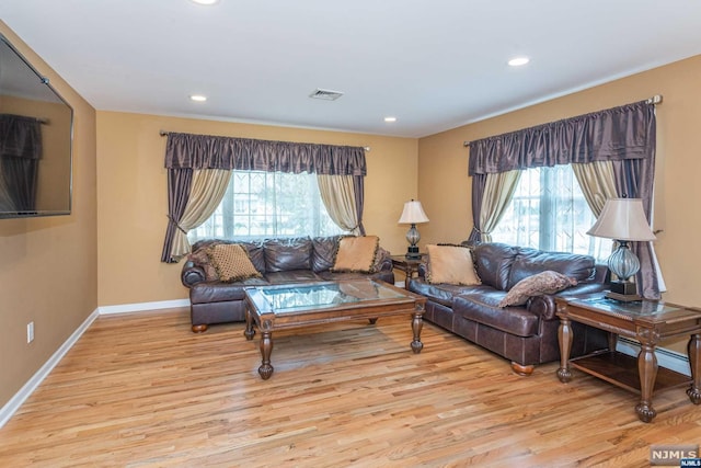 living room featuring baseboard heating, a healthy amount of sunlight, and light wood-type flooring