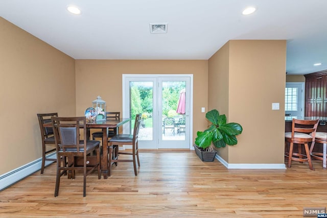 dining area with light wood-type flooring and a baseboard radiator