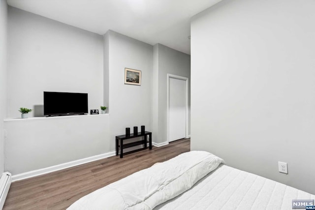 bedroom featuring a baseboard radiator and dark hardwood / wood-style floors