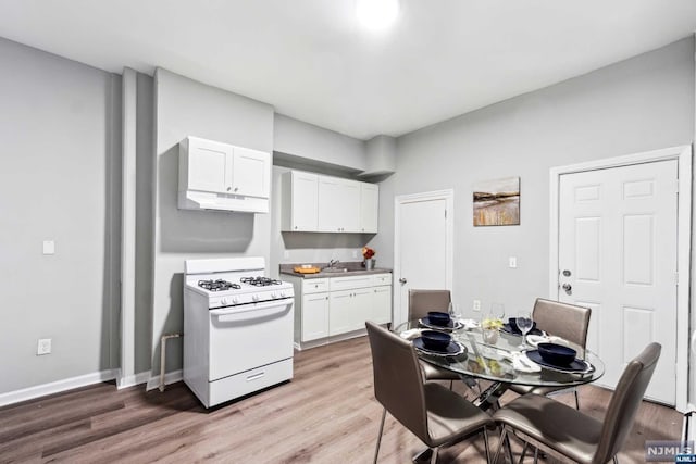 kitchen featuring white cabinetry, gas range gas stove, light hardwood / wood-style flooring, and sink