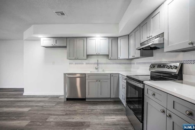 kitchen with backsplash, dark hardwood / wood-style flooring, stainless steel appliances, sink, and gray cabinets