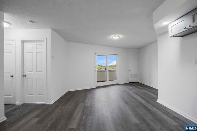 empty room with dark hardwood / wood-style flooring and a textured ceiling