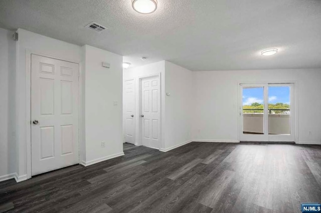 empty room featuring a textured ceiling and dark hardwood / wood-style floors