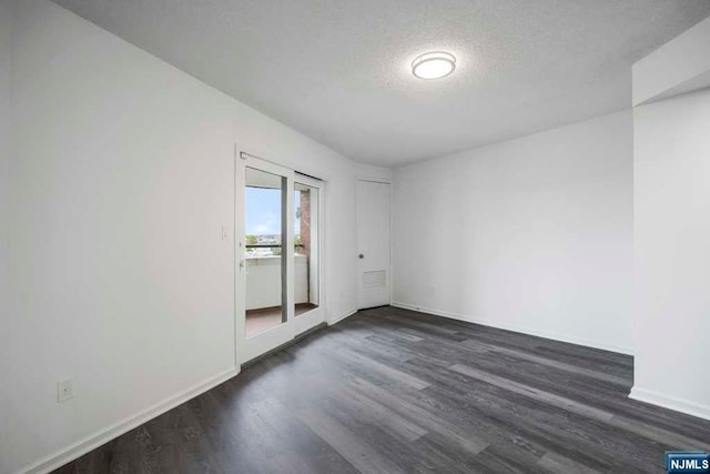 empty room with a textured ceiling and dark wood-type flooring