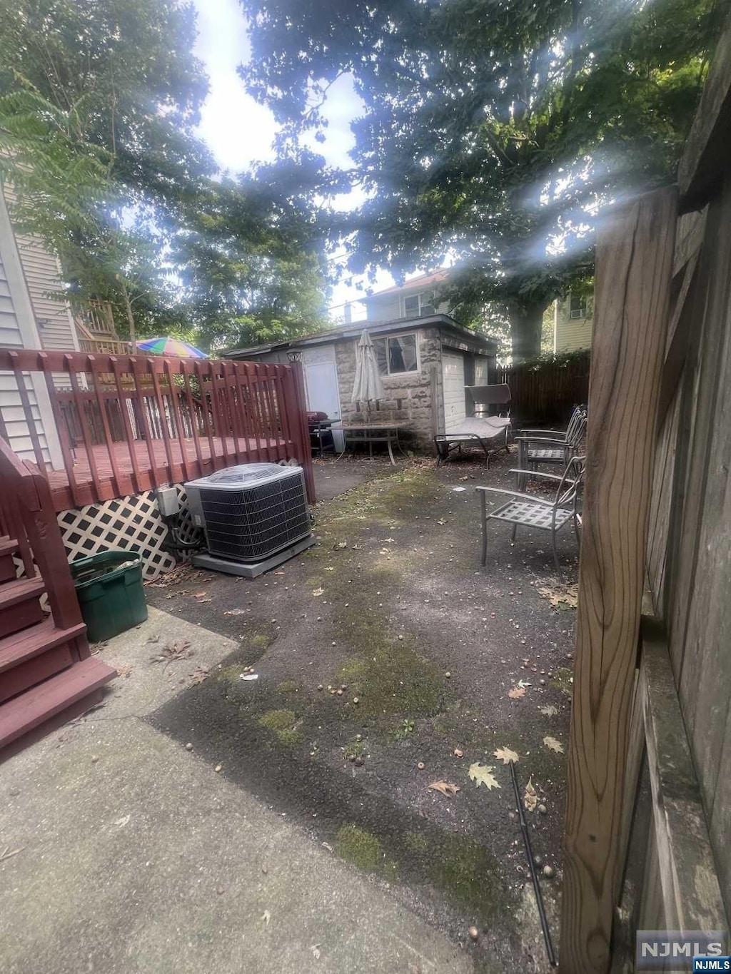 view of yard with central AC, a wooden deck, a patio, and an outdoor structure