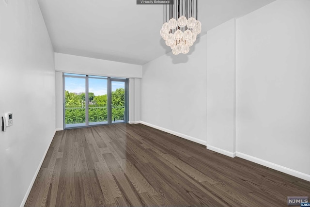 spare room with dark hardwood / wood-style floors and a chandelier