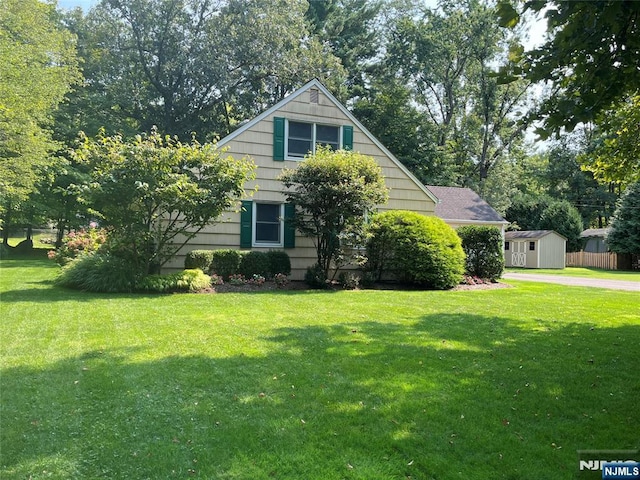 view of front of property with a storage unit, a front lawn, and an outbuilding