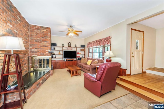 living area with brick wall, a fireplace, ornamental molding, and a ceiling fan