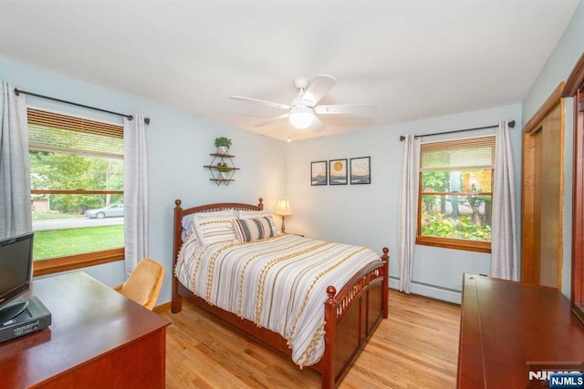 bedroom with light wood-style floors, ceiling fan, and baseboard heating