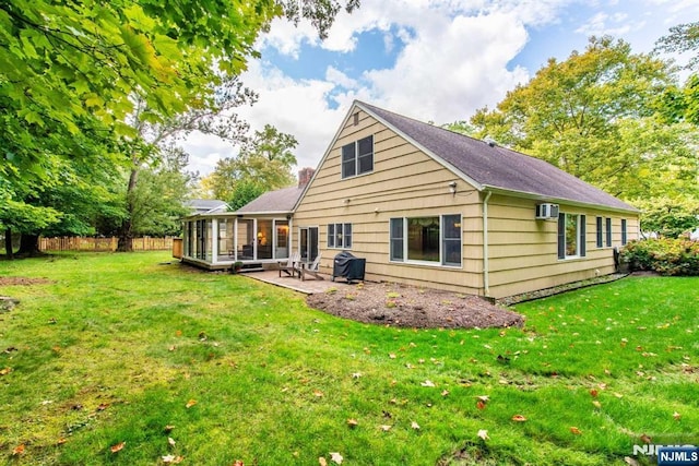 back of property featuring a wall unit AC, a sunroom, fence, a yard, and a patio area