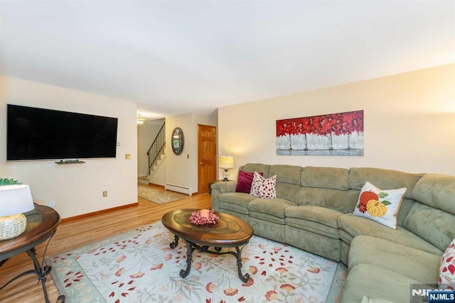 living area with a baseboard radiator, stairs, baseboards, and wood finished floors