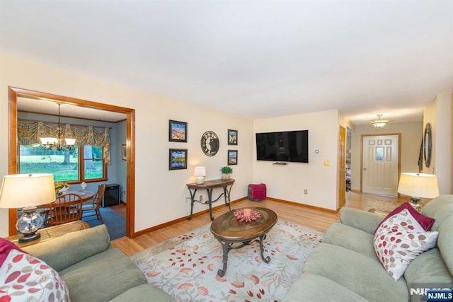 living area with light wood-type flooring, a notable chandelier, and baseboards