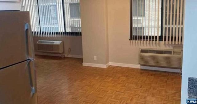 interior space with parquet flooring, white refrigerator, and a wall mounted air conditioner