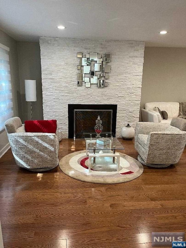 sitting room with hardwood / wood-style flooring and a stone fireplace