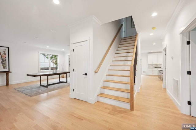 staircase featuring hardwood / wood-style floors and crown molding