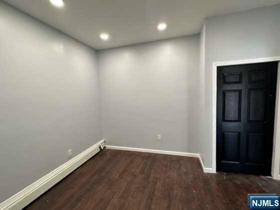 interior space featuring baseboard heating and dark wood-type flooring