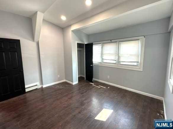 unfurnished bedroom with a baseboard radiator and dark hardwood / wood-style floors