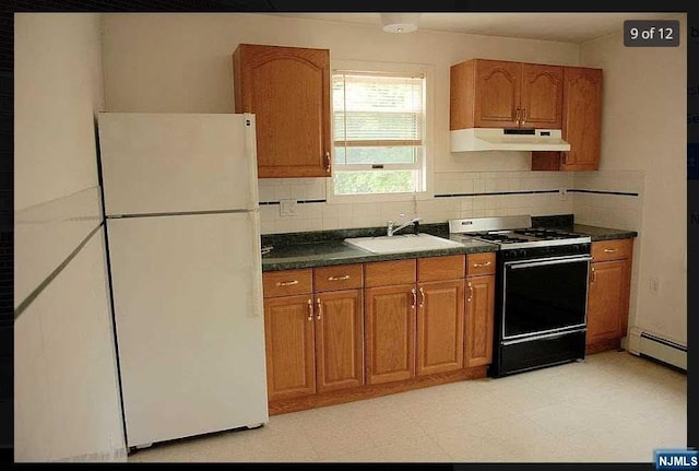 kitchen with backsplash, sink, a baseboard radiator, range, and white fridge