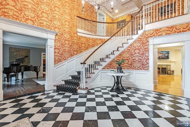 staircase featuring a wainscoted wall, a fireplace, and wallpapered walls