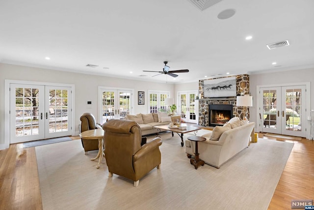 living room with a wealth of natural light, french doors, and light hardwood / wood-style flooring