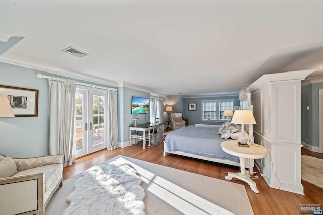 bedroom featuring hardwood / wood-style floors, access to exterior, ornamental molding, and multiple windows