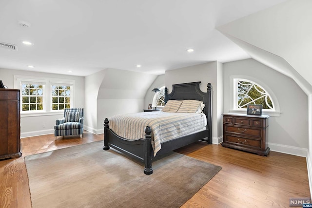 bedroom with light hardwood / wood-style floors, lofted ceiling, and multiple windows