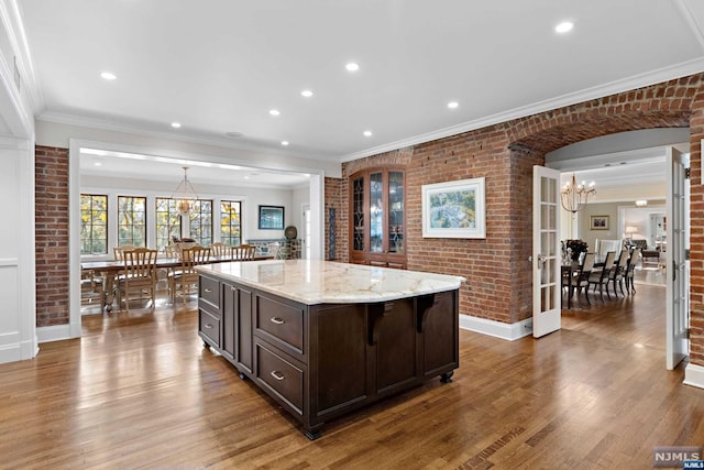 kitchen featuring dark brown cabinets, dark hardwood / wood-style flooring, a kitchen island, and brick wall