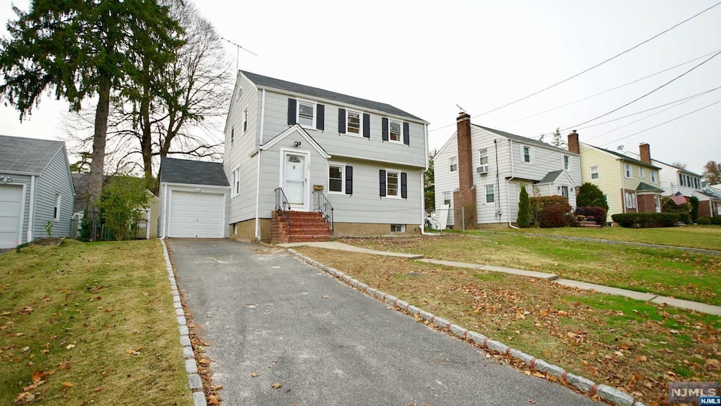 view of front of house featuring an outdoor structure, a front yard, and a garage