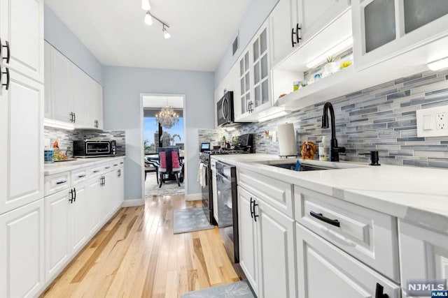 kitchen featuring sink, white cabinets, black appliances, and light wood-type flooring