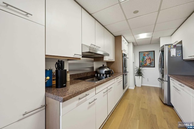 kitchen featuring white cabinetry, light hardwood / wood-style flooring, a paneled ceiling, white fridge, and black electric cooktop