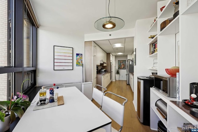 dining space featuring light hardwood / wood-style flooring and brick wall