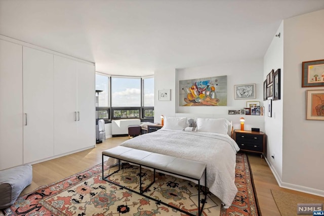 bedroom featuring expansive windows and light hardwood / wood-style floors