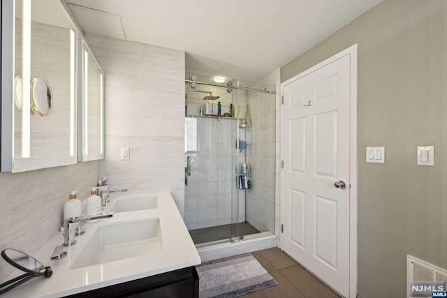 bathroom with tile patterned floors, vanity, a shower with door, and tile walls