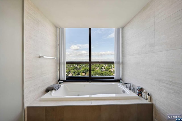 bathroom with a relaxing tiled tub and tile walls